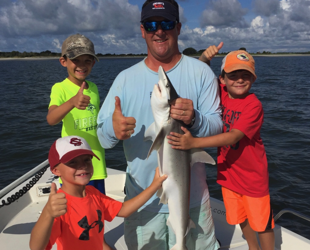3 young boys and captain with shark